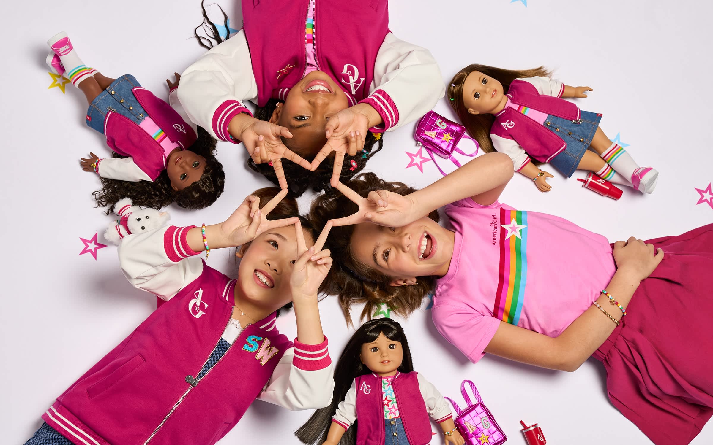Image of three girls laying on the floor while holding peace signs to create a star